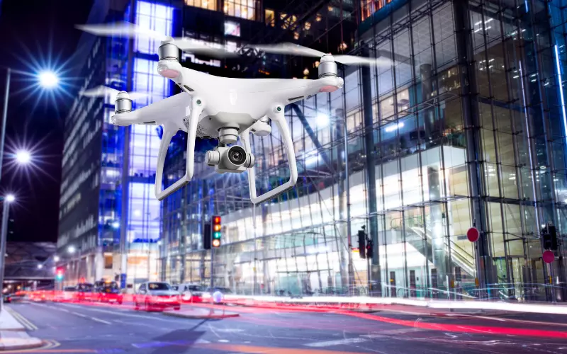 Dron volando sobre la calle de una ciudad a nivel bajo, al fondo se muestran edificios